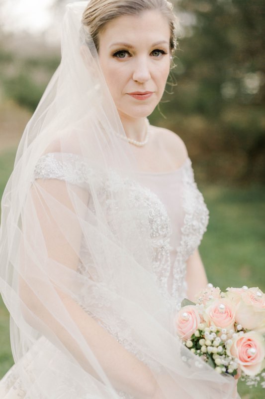 A beautiful bride poses for the camera with classic makeup including gorgeous false lashes.
