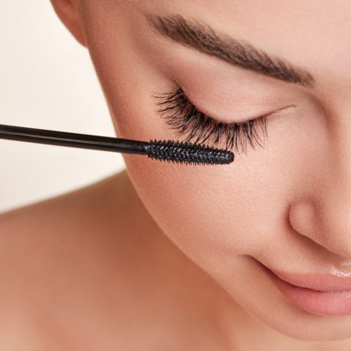 A young woman finishes putting mascara on her natural and false lashes for a beautiful, classic lash look.
